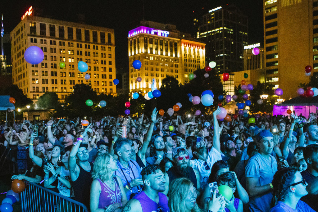 Completely packed crowd hitting tons of balloons overhead